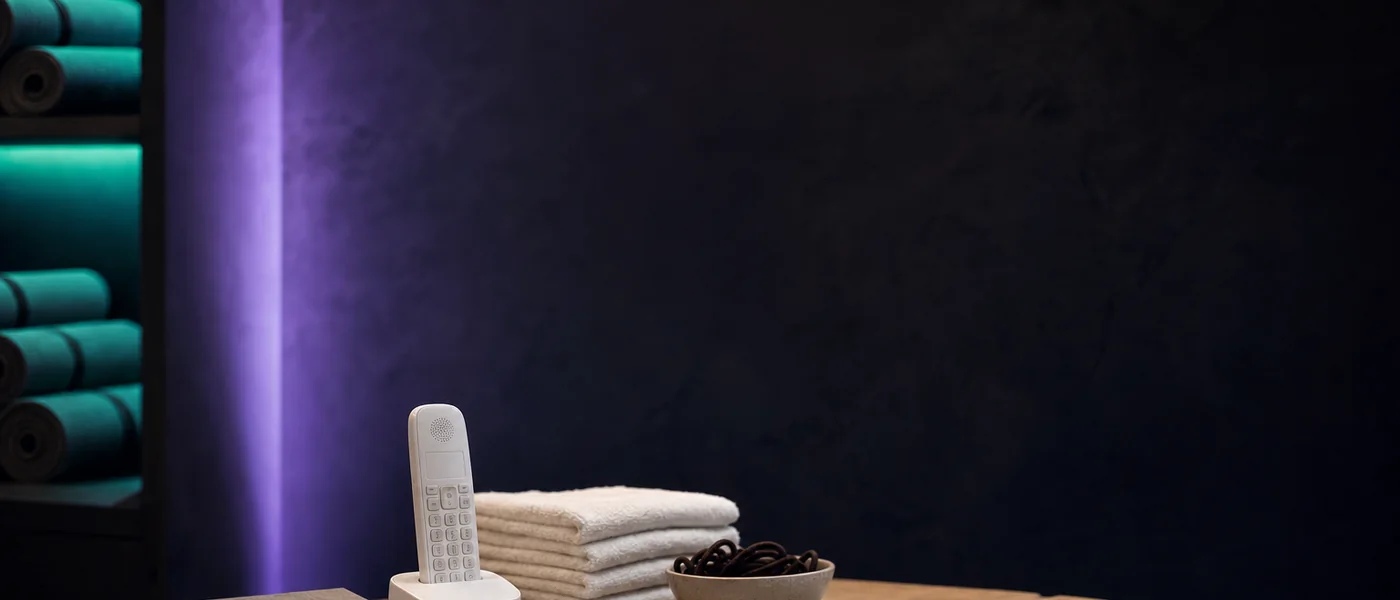A studio reception desk after closing, lit violet and teal, with an appointment book and a phone handset